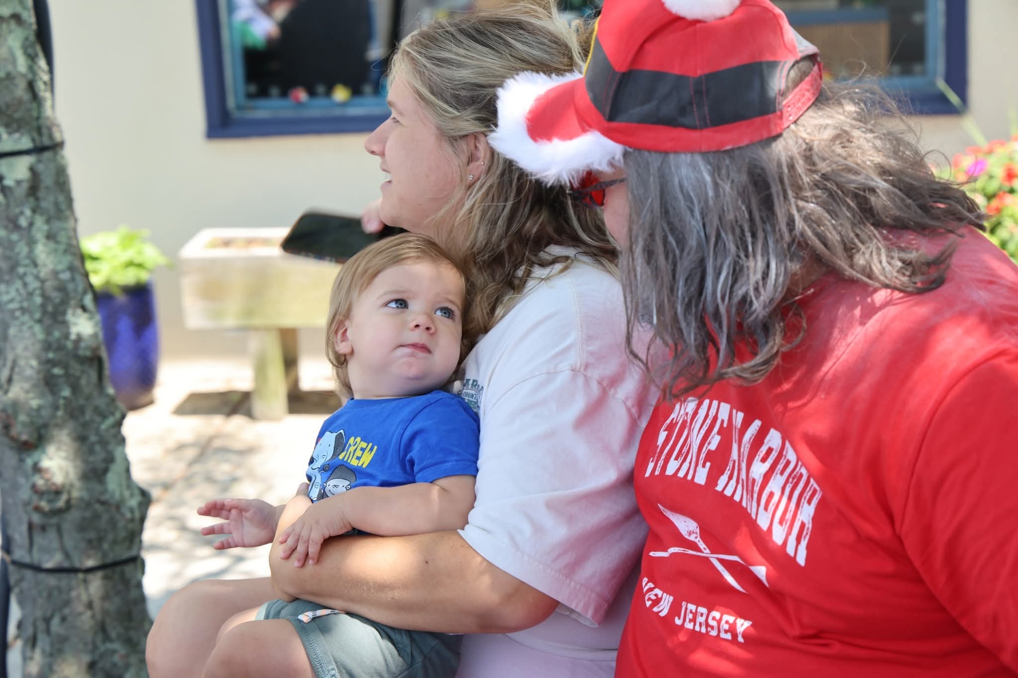 Cape May County Santa leaning in close with a mom and her toddler boy with big blue eyes