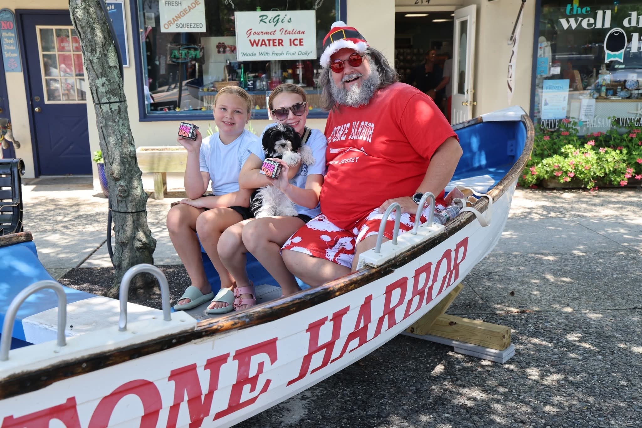 Cape May County Santa with two girls and a black-and-white puppy in the Stone Harbor boat holding RiGi's cups