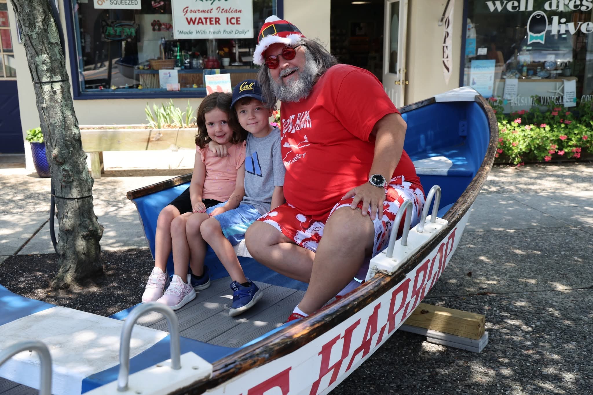 Cape May County Santa with a little girl in a peach shirt and a boy in a Cal hat in the Stone Harbor boat