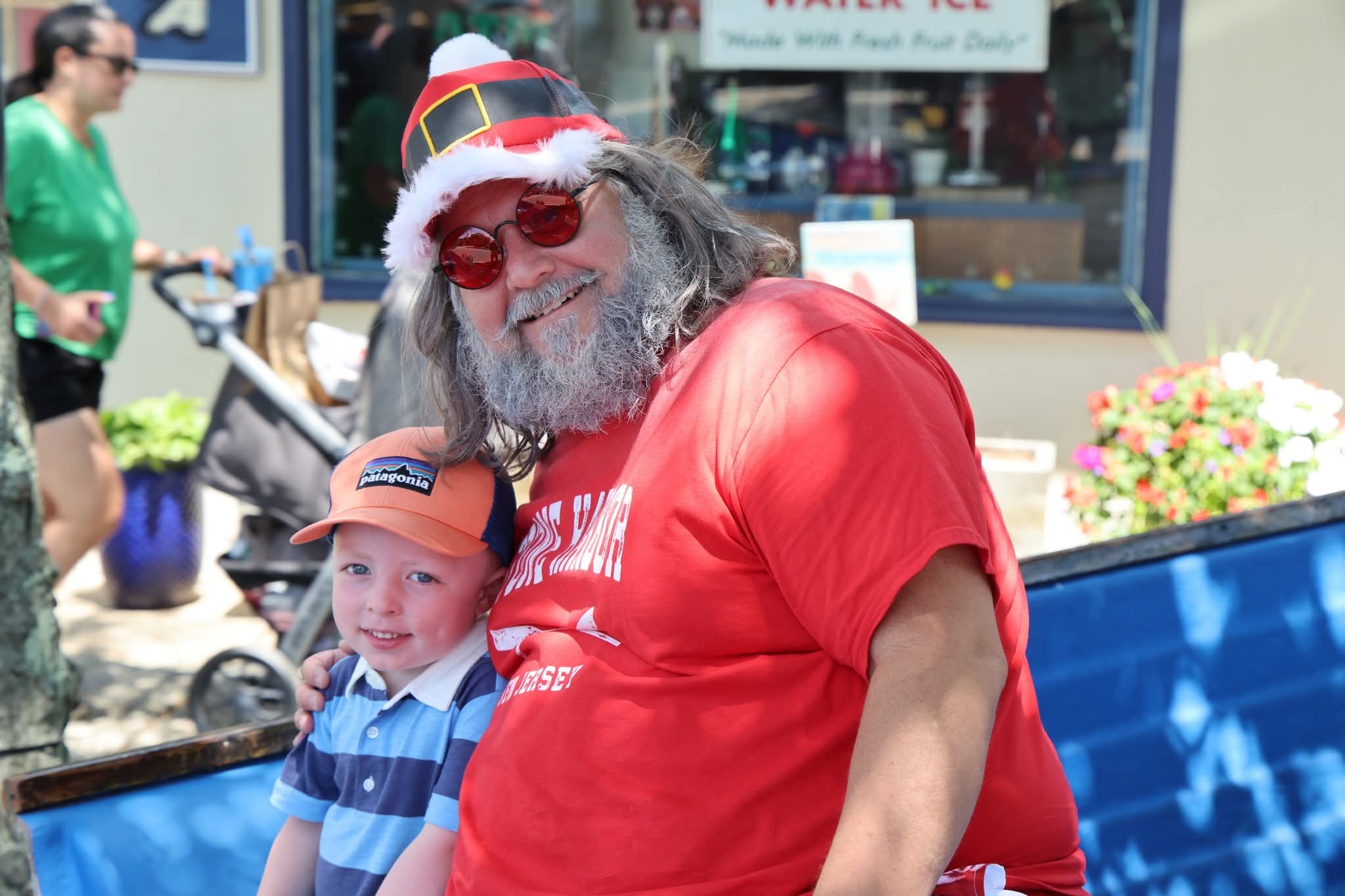 Cape May County Santa leaning in close with a little boy in an orange Patagonia hat near the Stone Harbor boat