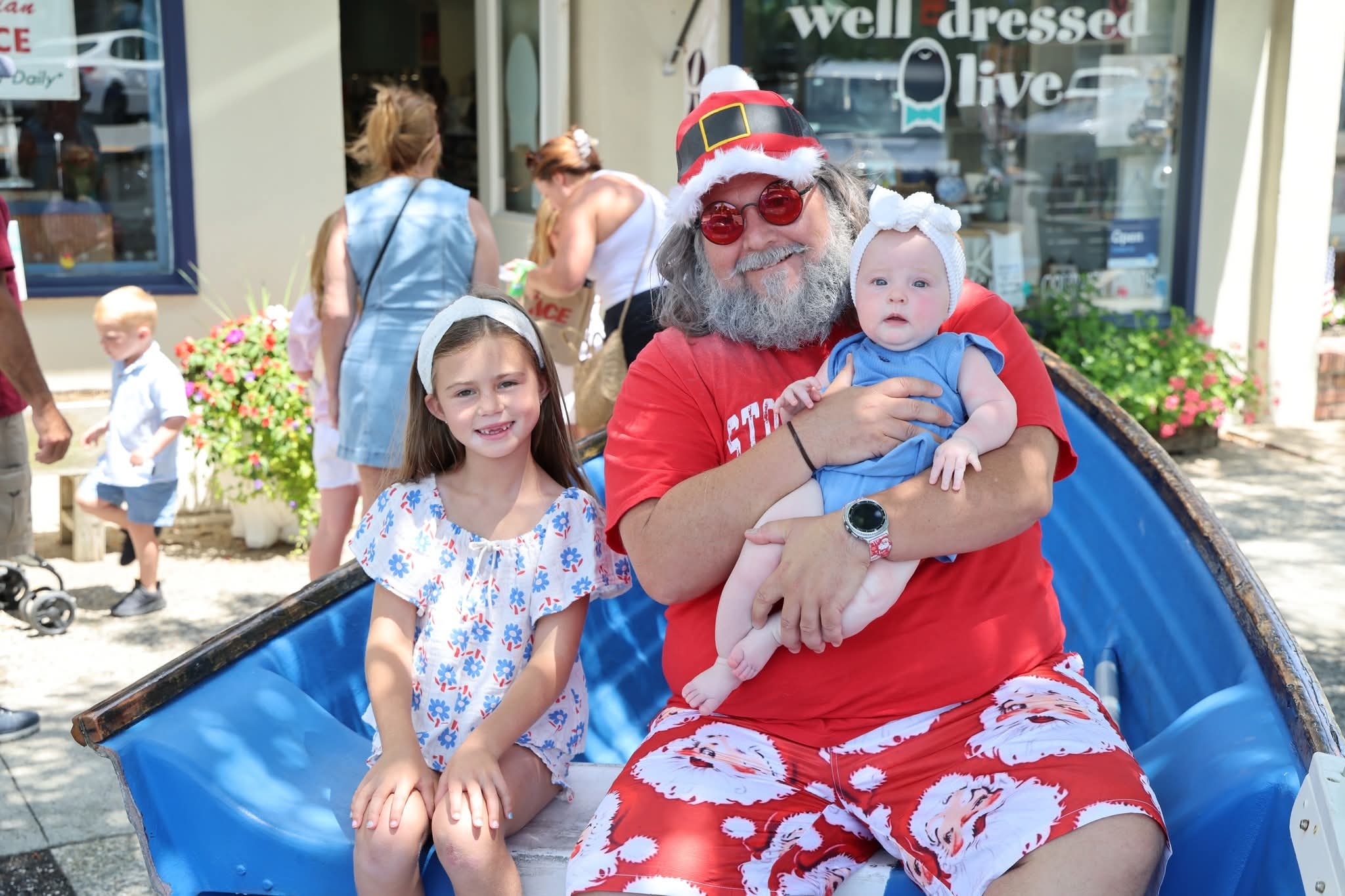 Cape May County Santa holding a newborn baby next to a girl in a floral dress in the Stone Harbor boat