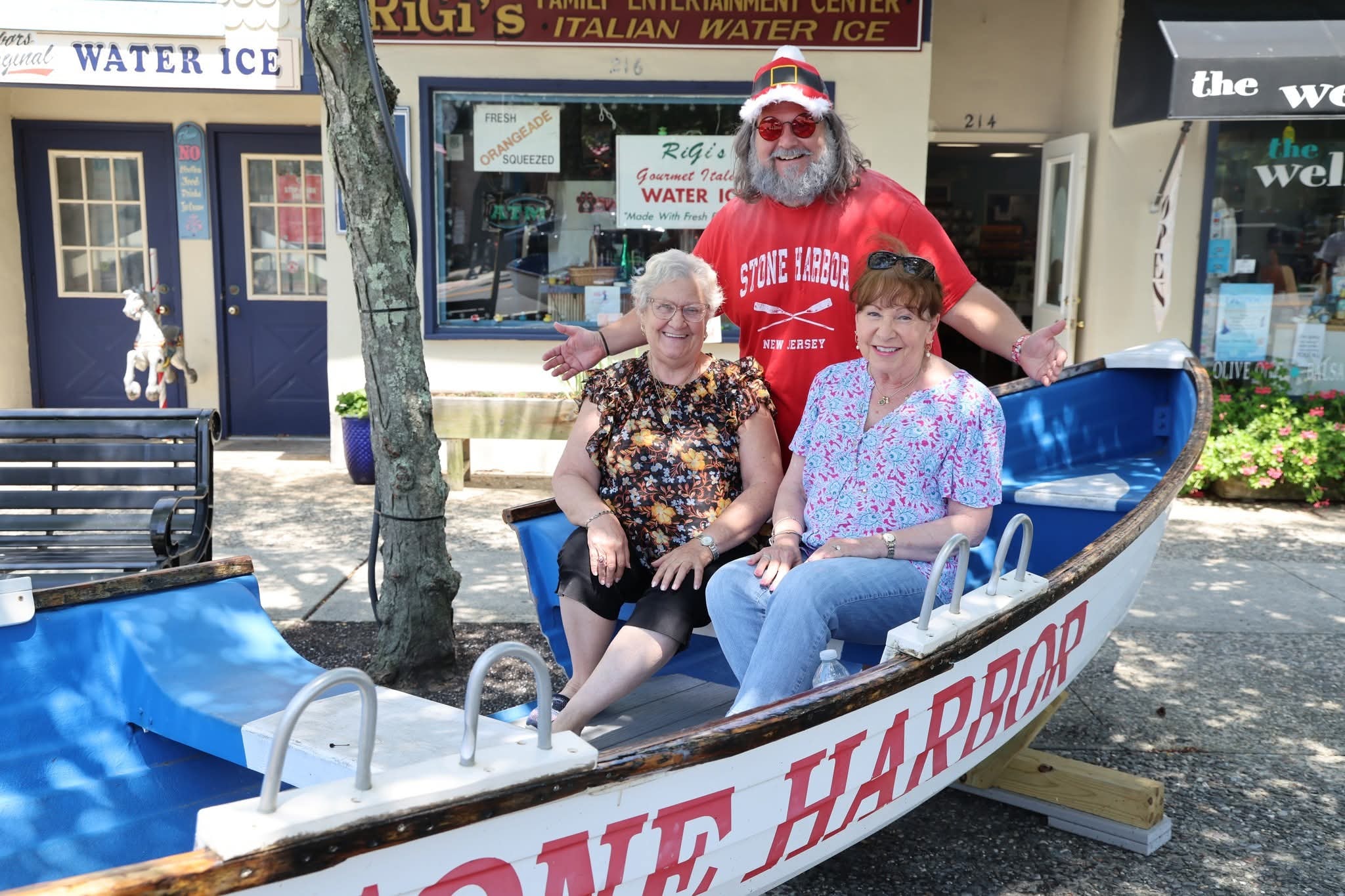 Cape May County Santa with arms wide open behind two older women in the Stone Harbor boat