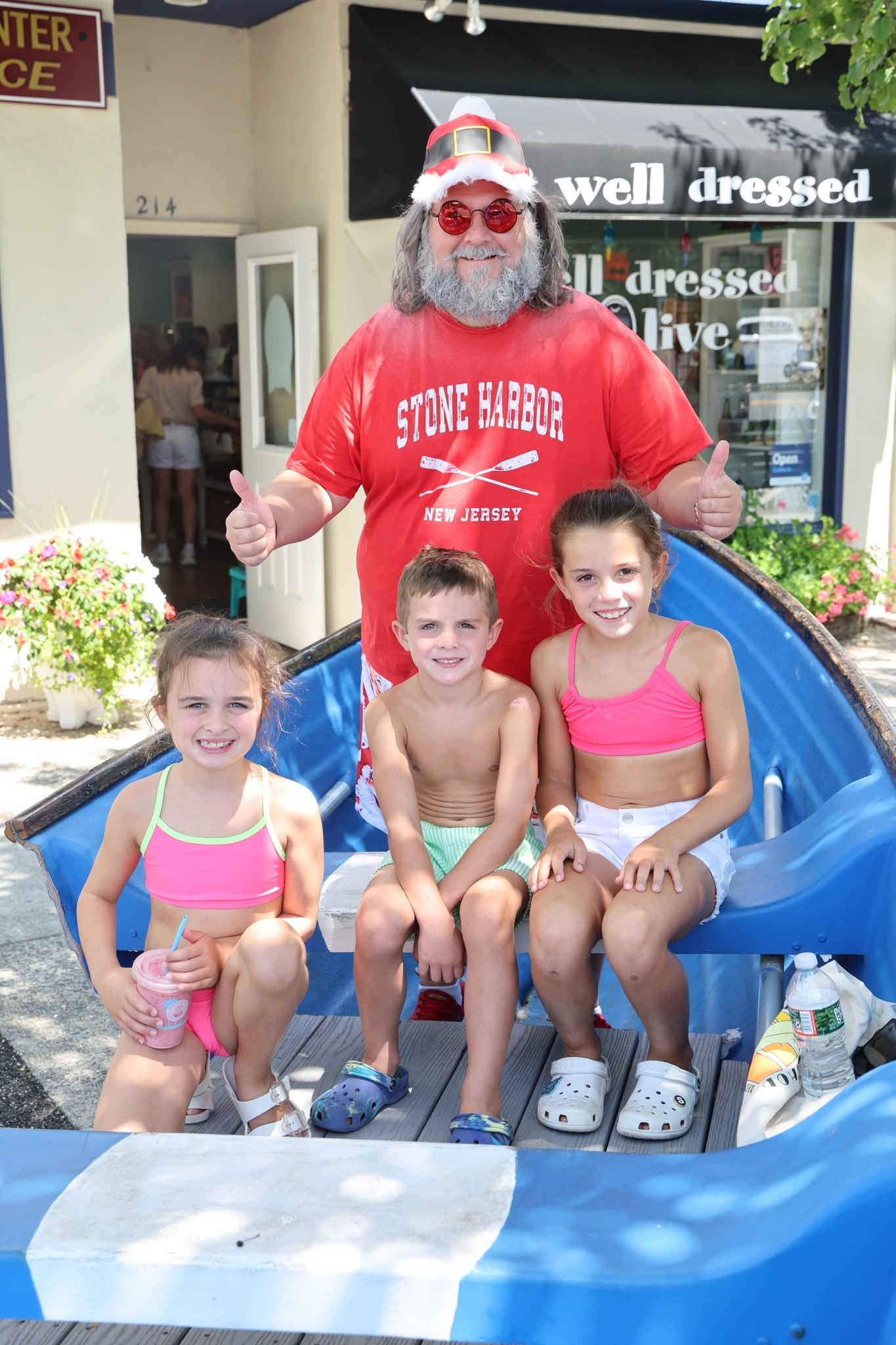 Cape May County Santa giving double thumbs up with three kids in swimsuits in the Stone Harbor boat