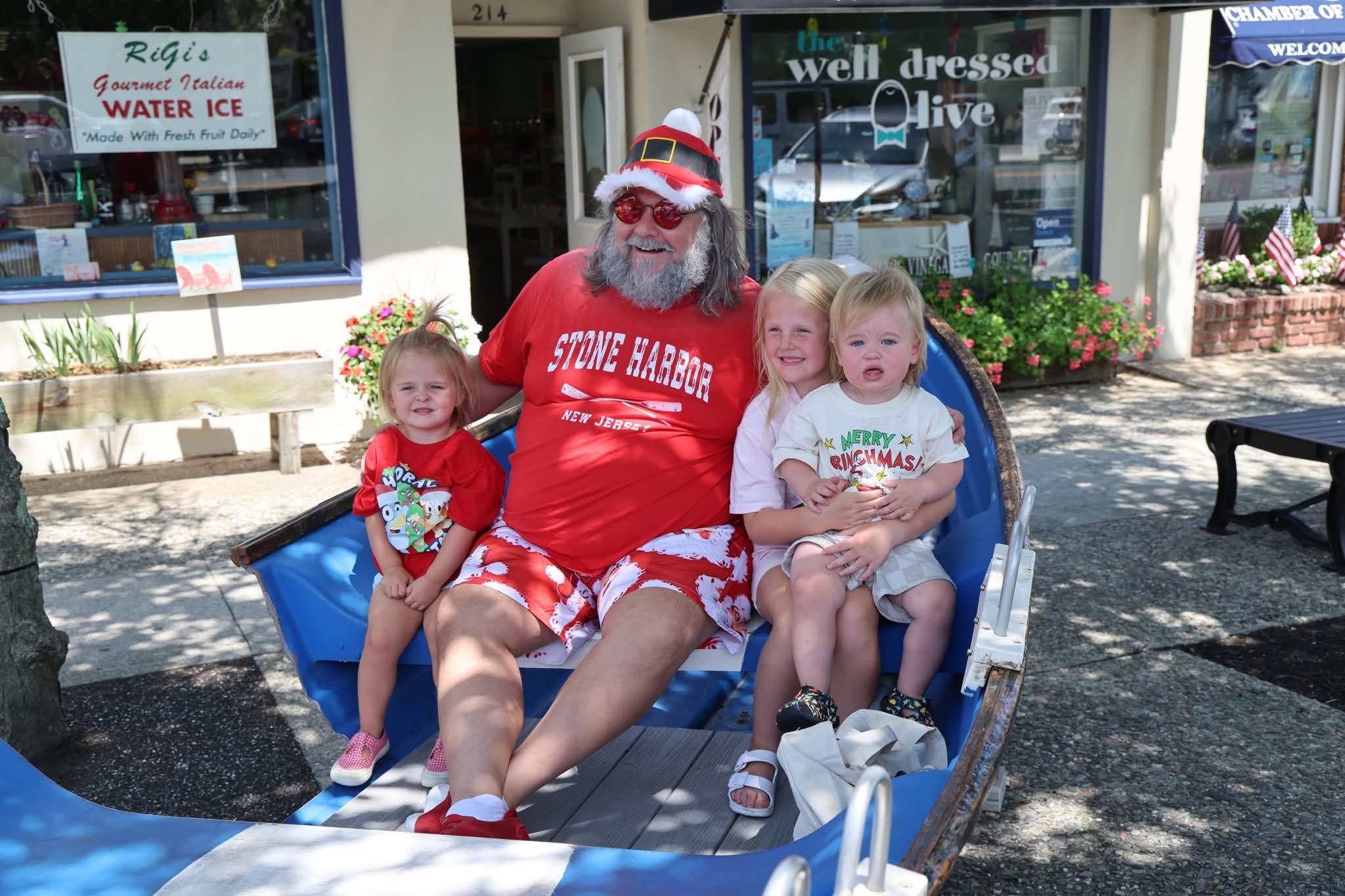 Cape May County Santa with three toddlers and young children in the Stone Harbor boat, one in a Merry Grinchmas shirt