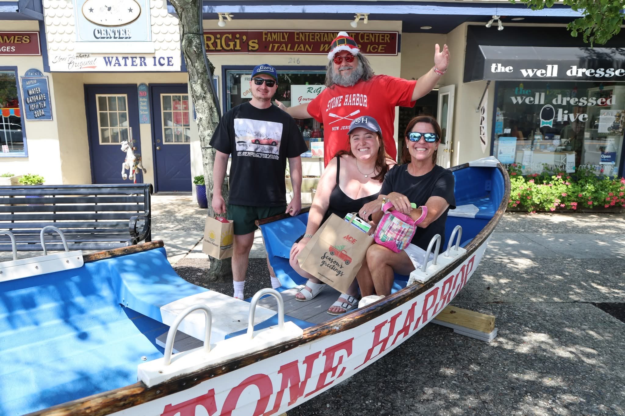 Cape May County Santa waving with a man and two women holding Trader Joe's Season's Greetings bags in the Stone Harbor boat