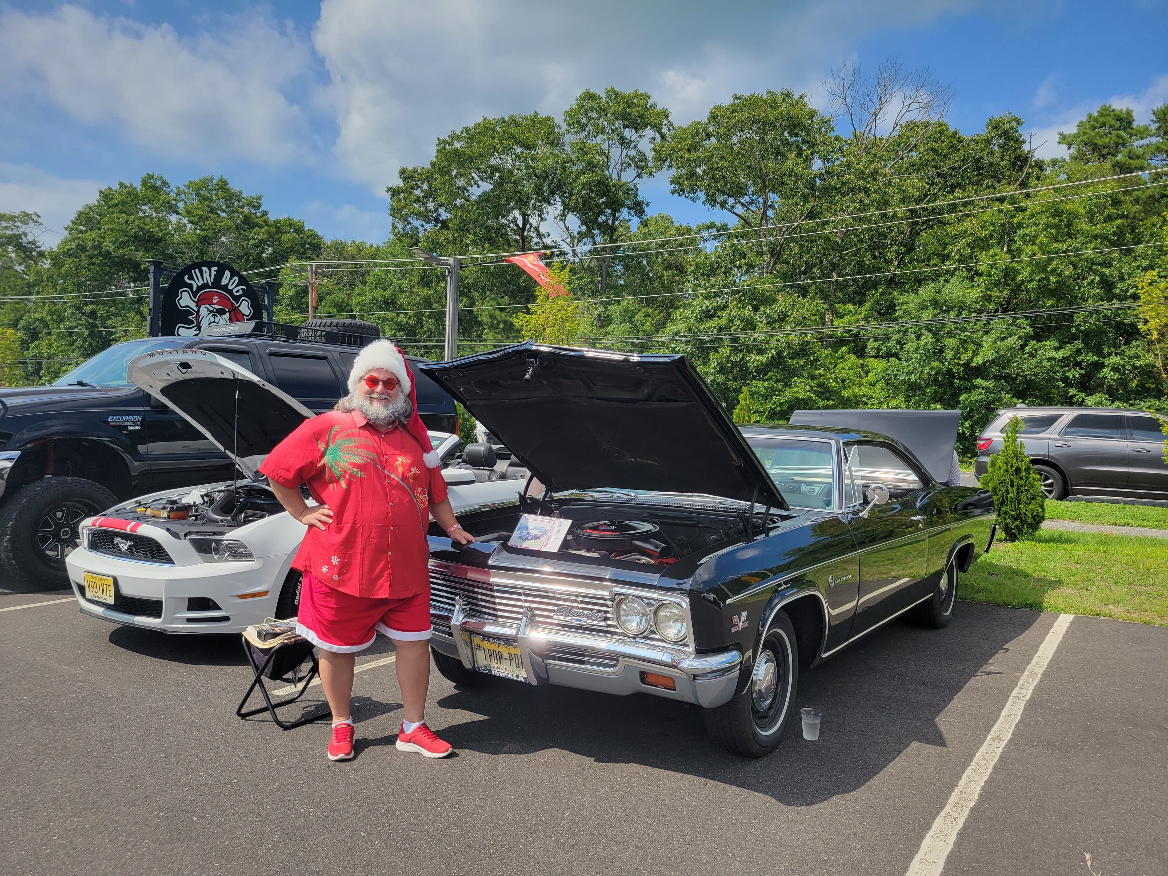 Cape May County Santa standing beside a classic black Chevy Impala at a car show