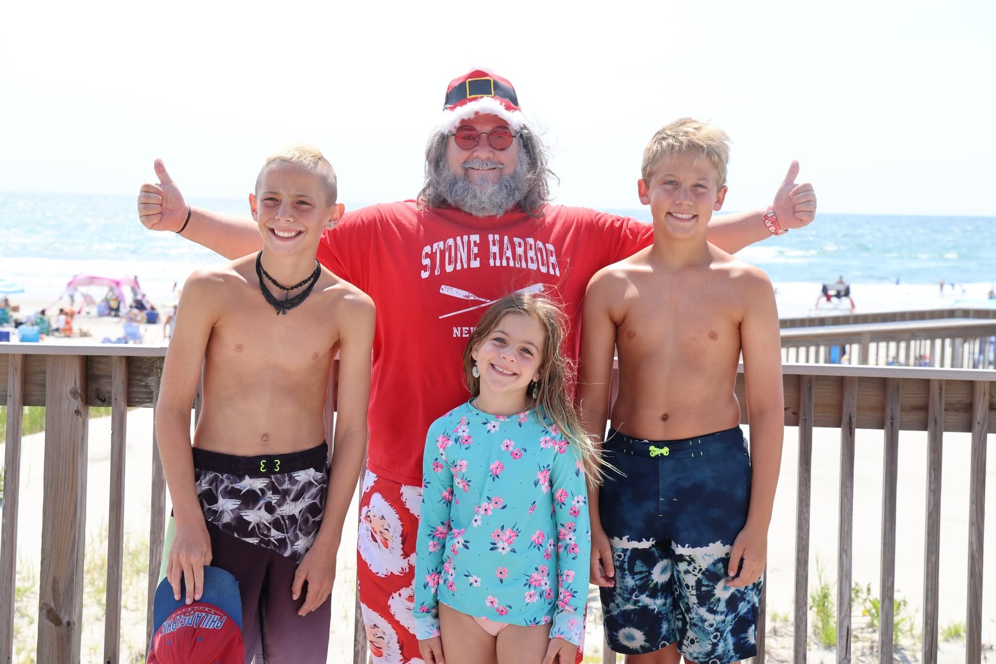 Cape May County Santa with three kids on the Stone Harbor boardwalk, two giving thumbs up