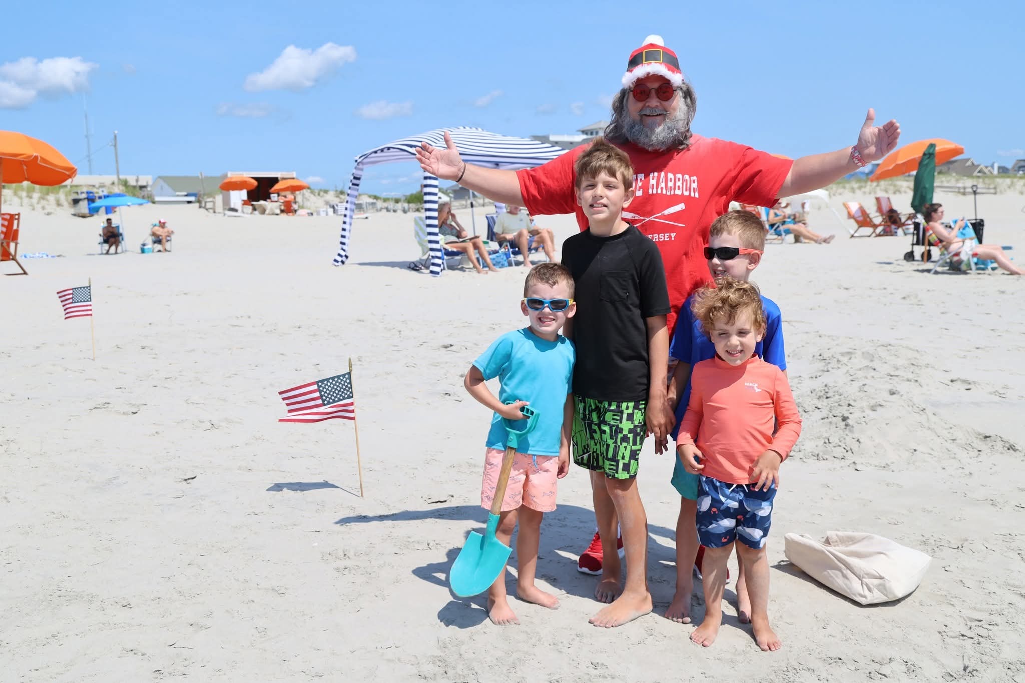 Cape May County Santa with arms wide open surrounded by four boys on the beach