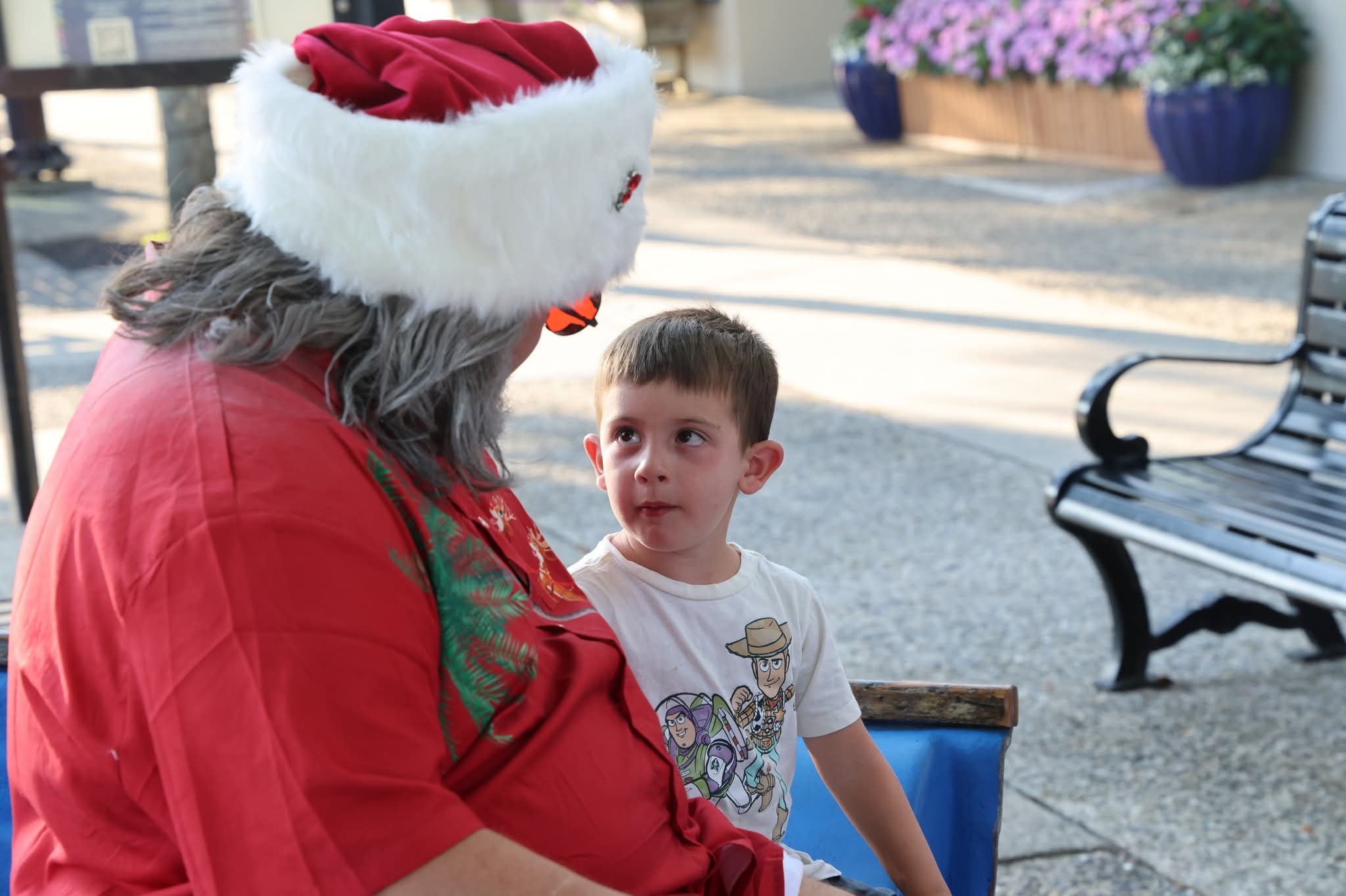 Cape May County Santa leaning in to talk with a young boy in a Toy Story shirt