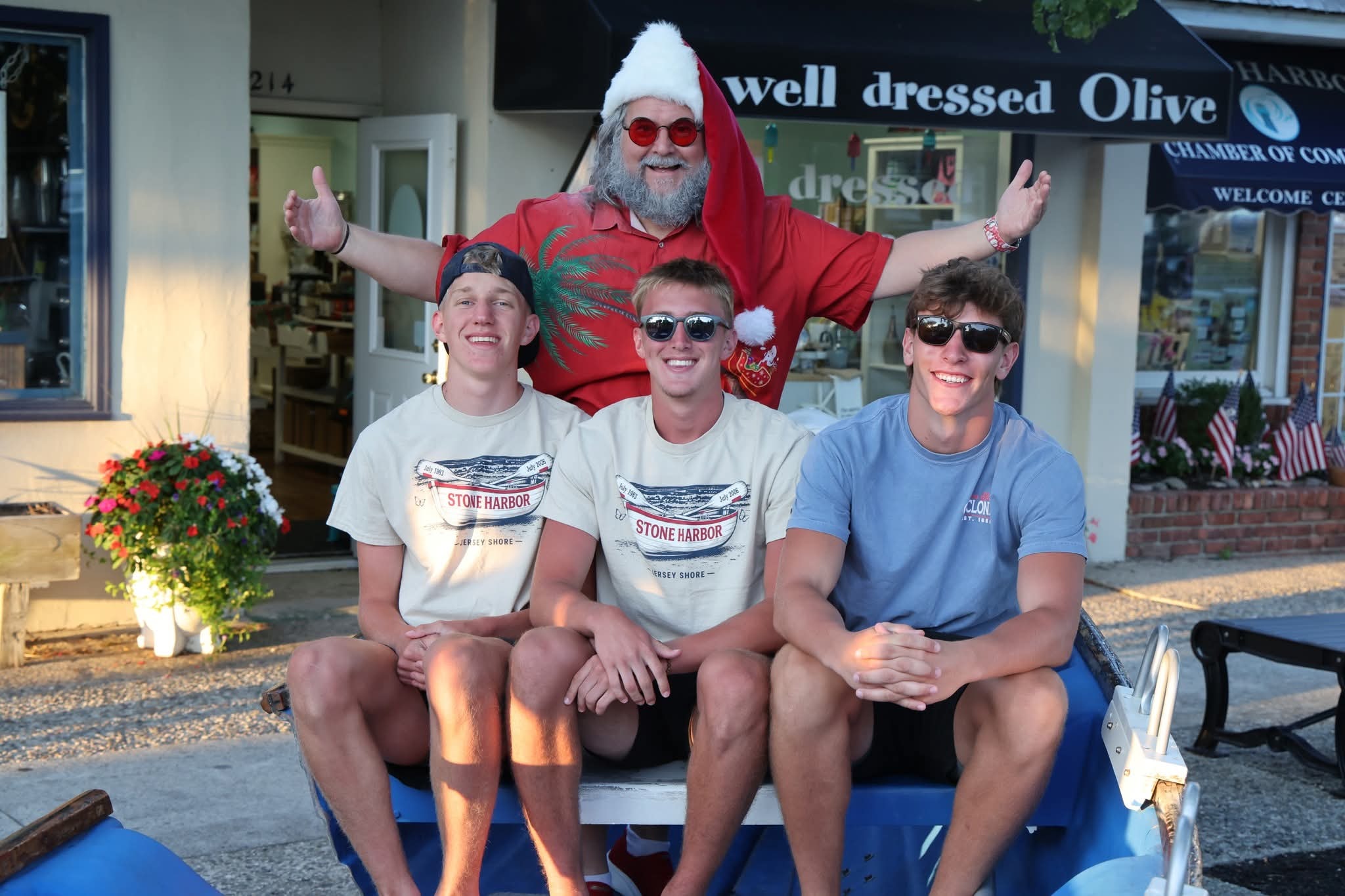 Cape May County Santa with arms wide open behind three teenage boys in Stone Harbor shirts