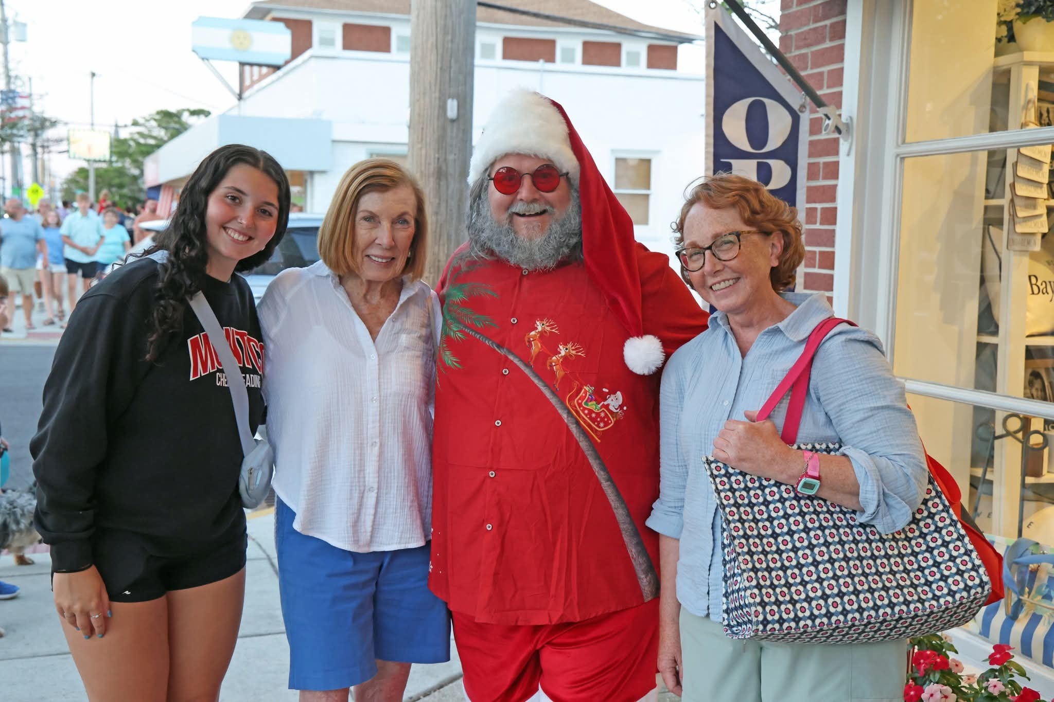 Cape May County Santa with a teenage girl in a Montco Cheerleading sweatshirt, an older woman, and a woman with a red bag on the Stone Harbor street